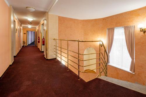 a hallway with a staircase in a building with a window at Wellness Hotel Jean De Carro in Karlovy Vary