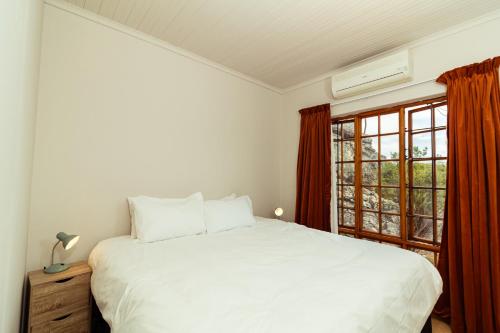 a bedroom with a white bed and a window at Wolfkop Nature Reserve in Citrusdal