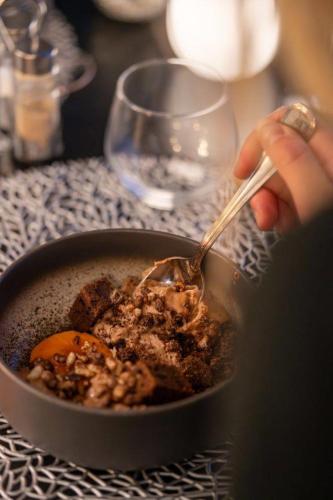 a person eating a bowl of food with a spoon at Hôtel Restaurant Le Madame in La Ferrière