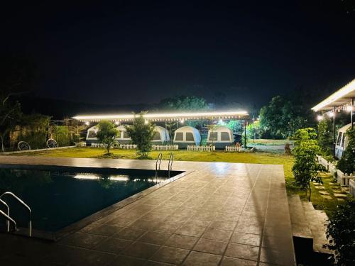 a building with a swimming pool at night at Kastur Farm in Karjat