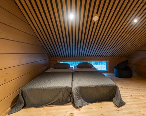 a bed in a room with a wooden ceiling at Black Work Levi Aapa in Kittilä