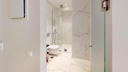 a white bathroom with a shower and a toilet at Maritime Suites in Hersonissos