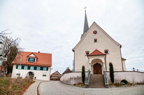a small white church with a steeple on a road at Tinas Ferienwohnung in Hergensweiler
