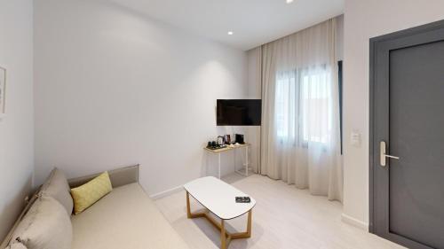 a white living room with a couch and a table at Maritime Suites in Hersonissos