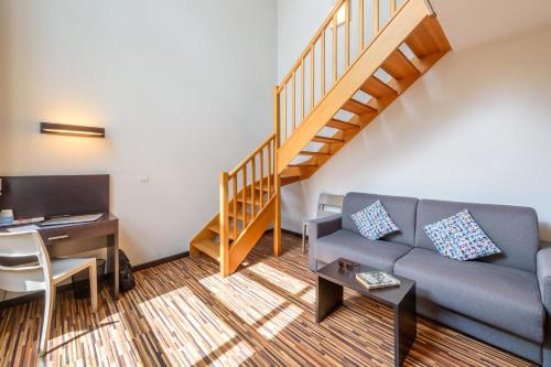 a living room with a couch and a staircase at Clarion Aparthotel Toulouse Le Parc de l'Escale in Toulouse