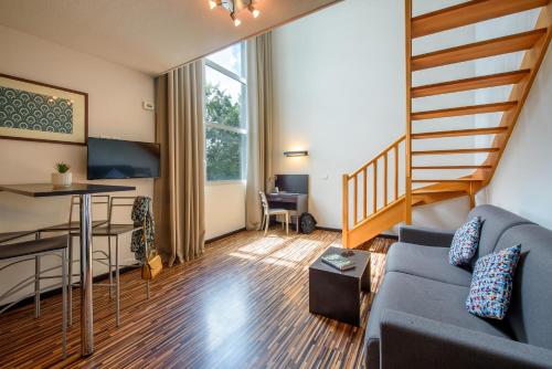 a living room with a blue couch and a table at Clarion Aparthotel Toulouse Le Parc de l'Escale in Toulouse