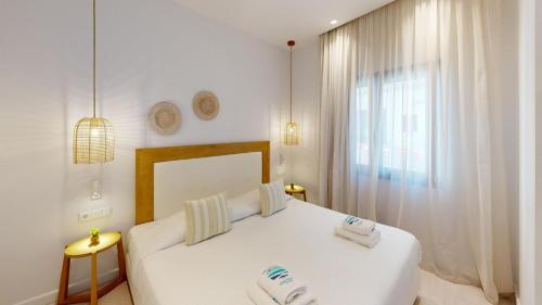 a white bedroom with a white bed and a window at Maritime Suites in Hersonissos