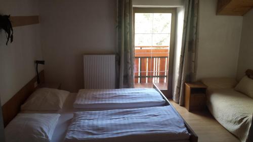 two beds in a room with a window at Pension Schönblick in Campo di Trens