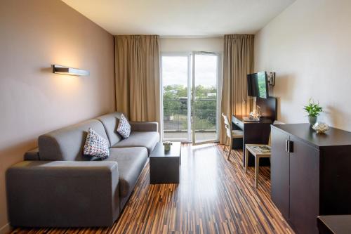 a living room with a couch and a tv at Clarion Aparthotel Toulouse Le Parc de l'Escale in Toulouse