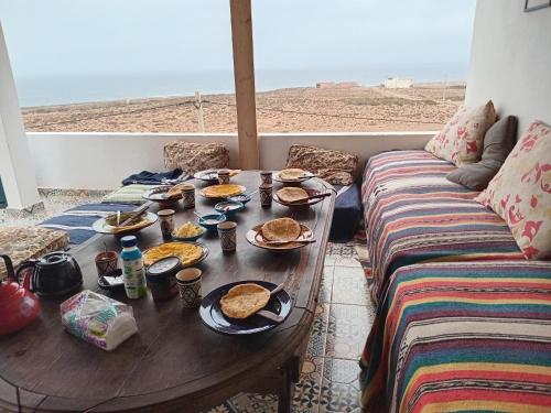 - une table avec des assiettes de nourriture et un canapé dans l'établissement EL Faro Surfstay, à Tamri