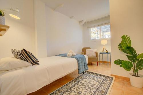 a bedroom with a white bed and a potted plant at Ancla 1 in Port d’Andratx