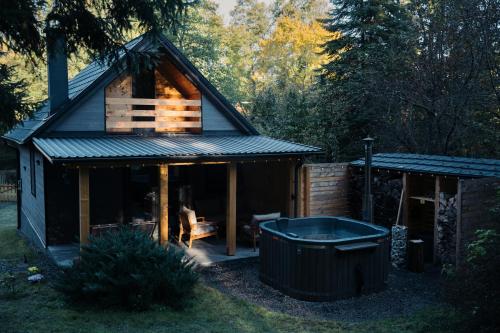 a small cabin with a hot tub in the yard at Szürke Szarvas in Szuha