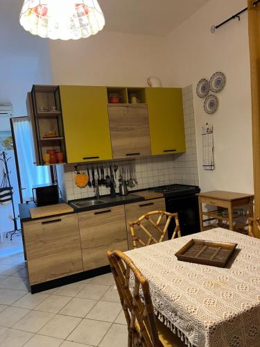a kitchen with yellow cabinets and a table with a tablecloth on it at La casa sotto la torre in Chia