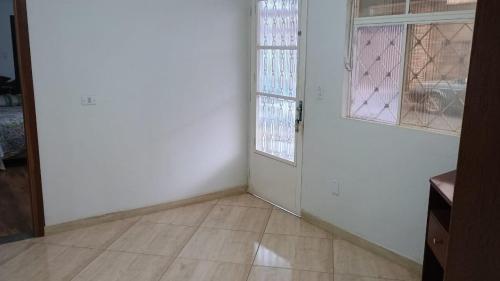 an empty room with a door and two windows at Casa Temporada Poços de Caldas in Poços de Caldas