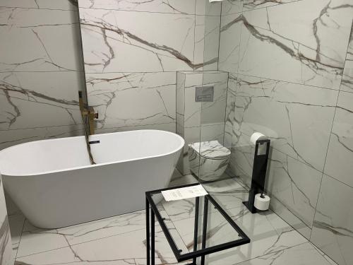 a white bath tub in a bathroom with marble walls at Hotel Lantier Wellness & Spa in Bytom