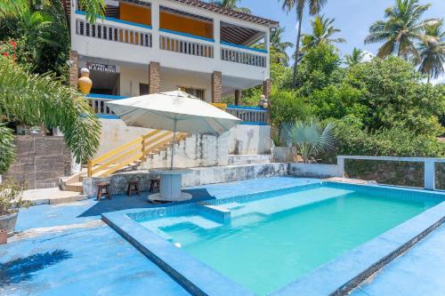 a swimming pool with an umbrella and a house at Casa c/ Piscina-4 Quartos-Barra de Catuama-SH101M in Ponta do Funil