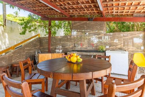 a wooden table with a bowl of fruit on a patio at Casa c/ Piscina-4 Quartos-Barra de Catuama-SH101M in Ponta do Funil