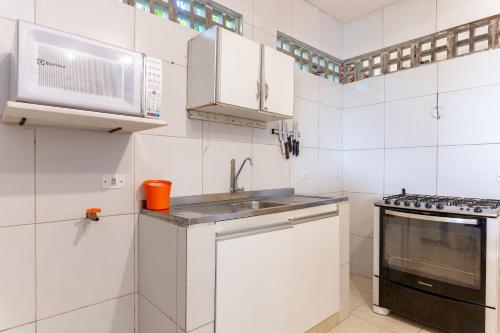 a white kitchen with a sink and a microwave at Casa c/ Piscina-4 Quartos-Barra de Catuama-SH101M in Ponta do Funil