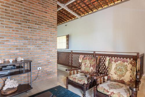 a living room with two chairs and a brick wall at Casa c/ Piscina-4 Quartos-Barra de Catuama-SH101M in Ponta do Funil