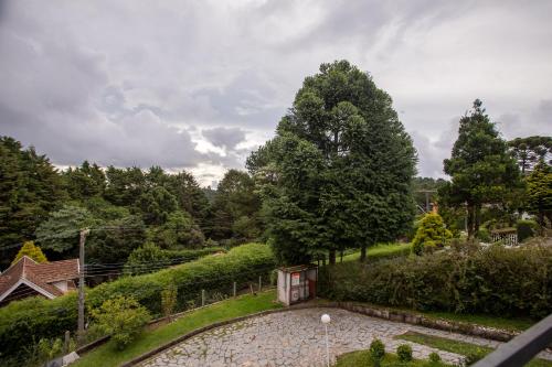 a garden with a stone walkway and trees at Villa Hegus chales com hidro ar lareira in Campos do Jordão