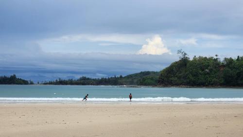 two people walking in the water on a beach at Kelambu Beach Villa in Kudat