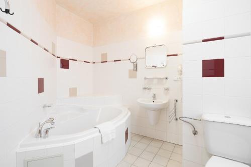 a white bathroom with a tub and a sink at Wellness Hotel Jean De Carro in Karlovy Vary