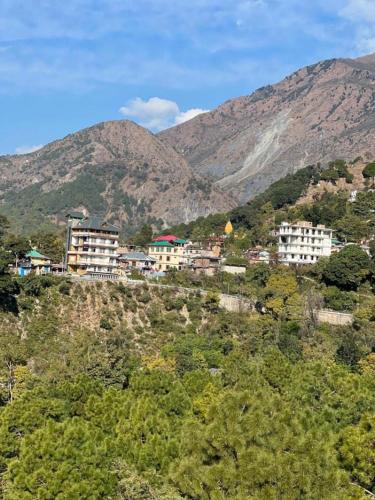 a group of buildings on a hill with mountains at The Crown in Dharamshala