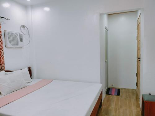 a white bedroom with a bed and a door at Family Suite 4-6 Pax GLENMARK'S Homestay near the beach in Pagudpud