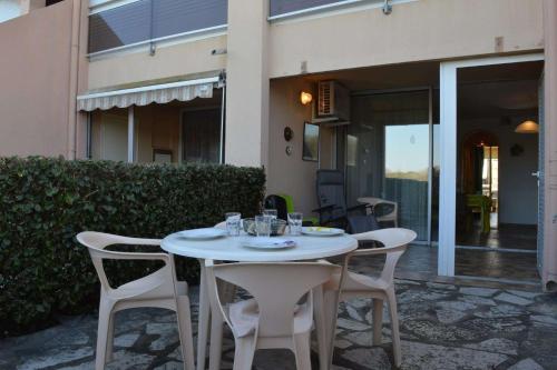 une table et des chaises blanches devant une maison dans l'établissement Appartement 2 pièces cabine 6 personnes SAINT CYPRIEN SC150-138, à Saint Cyprien Plage