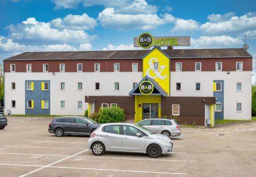 a hotel with cars parked in a parking lot at B&B HOTEL Troyes Saint-Parres-aux-Tertres in Saint-Parres-aux-Tertres