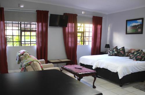 a bedroom with a bed and a couch and a table at Urban Gardens in Gqeberha
