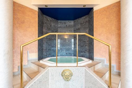 a jacuzzi tub in a room with a stone wall at Wellness Hotel Jean De Carro in Karlovy Vary