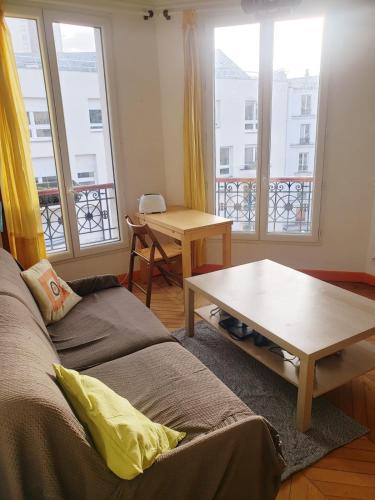 - un salon avec un canapé, une table et des fenêtres dans l'établissement Un petit coin de soleil chez l'habitant, à Paris