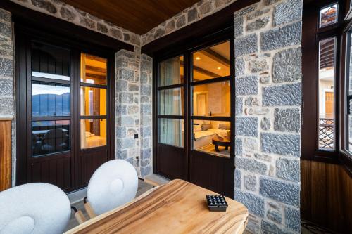 a dining room with a stone wall and a table and chairs at Maison Michelangelo in Arachova