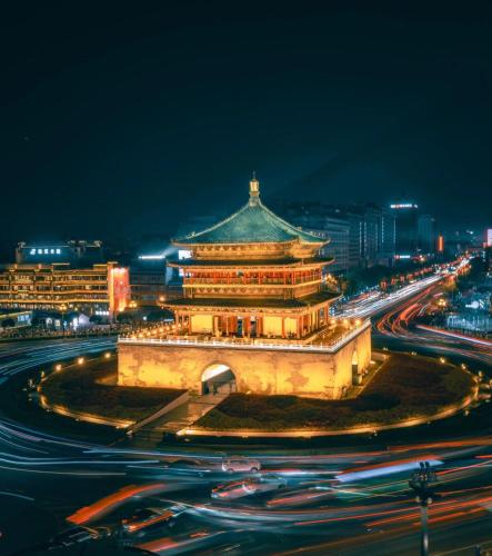 a building with a tower in a city at night at HeSu Hidden Art Hotel & Suites - Near Bell Tower & Ideal Location-Spacious rooms featuring King or Double Queen beds -Exclusive Two&Three-Bedroom Suites with Expansive Living Rooms for Group Gathering-Kitty Cuddles & Coffee Gift -Seamless Journey Planning in Xi'an