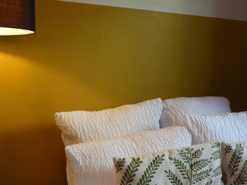 a bed with white pillows against a yellow wall at Guesthouse De Wissen in Dilsen-Stokkem