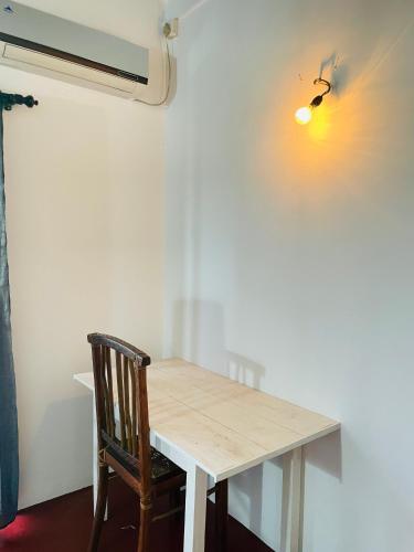 a wooden table with a chair next to a wall at Villa White in Polhena