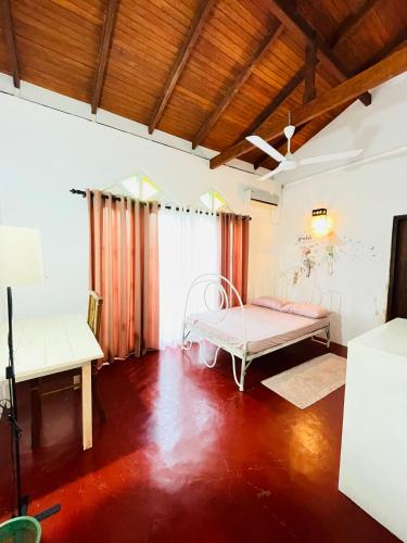 a bedroom with a bed in a room with wooden floors at Villa White in Polhena