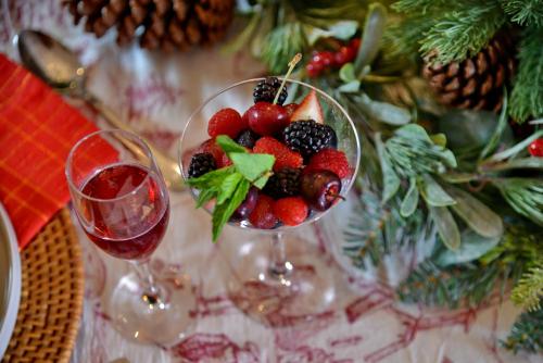 a glass bowl of fruit next to two glasses of wine at The Vineyard on Ballito in Ballito