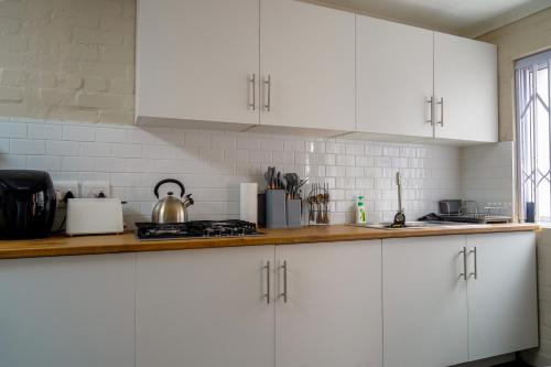 a kitchen with white cabinets and a counter top at Cozy Cottage in Constantia in Cape Town