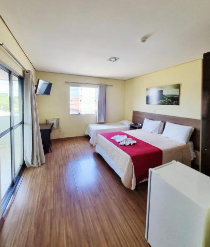 a hotel room with two beds and a television at Pousada Coqueiral in Aracruz