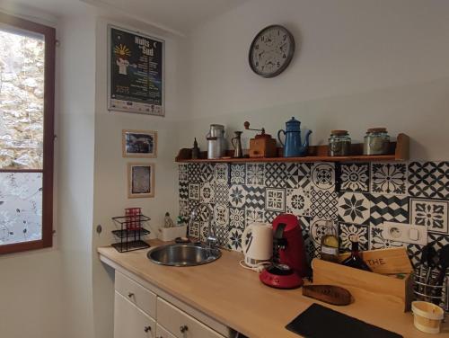 a kitchen counter with a sink and a clock on the wall at Aloha in Vence