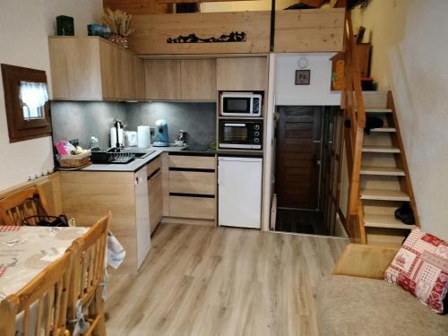 une petite cuisine avec un escalier dans une petite maison dans l'établissement Appartement cosy 4 pers avec mezzanine, balcon exposé sud, WiFi, centre Valloire, près des remontées - FR-1-263-27, à Valloire