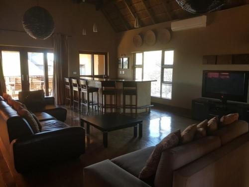 a living room with couches and a table and a television at Zebula Golf and Wildlife Estate - Squirrel Pandemonium Pax 12 - Moi Signature Luxury villa in Mabula
