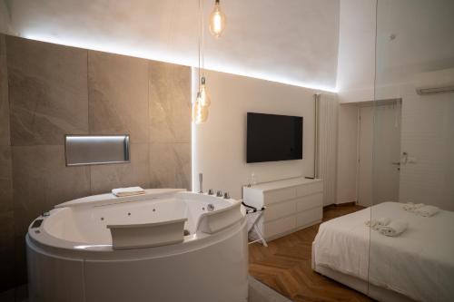 a bathroom with a tub and a bed and a tv at Enjoyhousebracciano suite2 in Bracciano