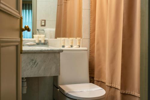 a bathroom with a toilet and a sink and a mirror at Hotel Los Españoles Plus in Santiago