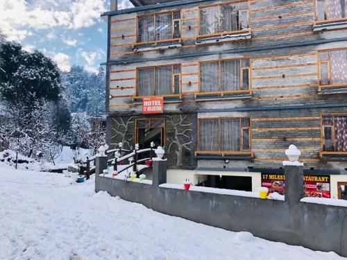 a wooden building with snow in front of it at Hotel 17 Miles Stone, Manali By Shivaneel Hospitality in Manāli