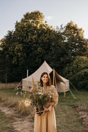 a woman holding a bouquet of flowers in front of a tent at Villa Huno Glamping in Borre