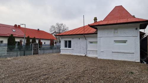 a white house with a red roof on a dirt yard at DreamPlace Airport & Therme 2 in Otopeni