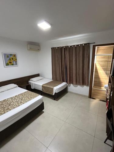 a room with two beds and a window at Hotel Holiday Foz in Foz do Iguaçu